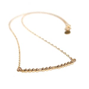 May include: A gold necklace with a delicate chain and a row of small gold beads.