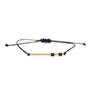 May include: A black string bracelet with gold beads and black beads.