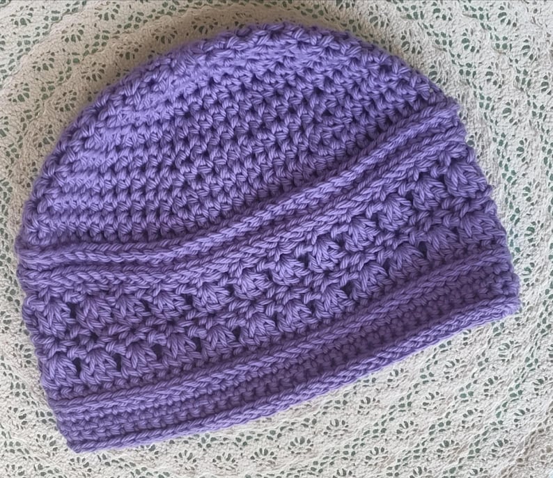 Puede incluir: Un gorro de ganchillo hecho a mano, de color lavanda. El gorro presenta un patr&oacute;n de puntada texturizada con un borde acanalado y detalles decorativos. El gorro suave y c&aacute;lido es perfecto para el clima fr&iacute;o y a&ntilde;ade un toque de encanto artesanal a cualquier atuendo.