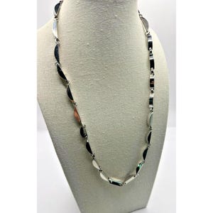 May include: A silver-toned necklace with a repeating pattern of half-moon shaped links. The necklace is displayed on a white mannequin bust against a white background. The links are connected by small, rectangular bars.