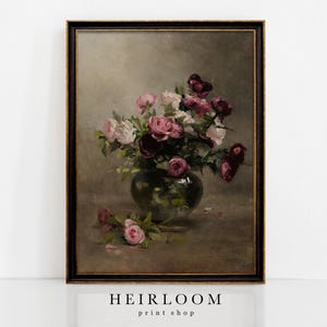May include: A framed vintage still life painting depicting a bouquet of pink and burgundy roses in a green glass vase. The artwork has a dark frame and a neutral background. The text "HEIRLOOM print shop" is at the bottom.