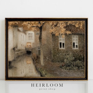 May include: Framed vintage print of a European canal scene. The artwork features buildings with windows, a tree with golden leaves, and a reflection in the water. The frame is dark with gold accents. The text "HEIRLOOM print shop" is at the bottom.
