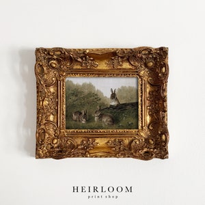 May include: A framed print featuring a pastoral scene with several rabbits in a forest setting. The artwork is enclosed in an ornate, gold-colored frame. The text "HEIRLOOM print shop" is at the bottom of the image.