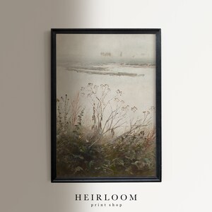 May include: A framed landscape painting with a muted color palette. The artwork depicts a misty, overcast scene with a body of water and sparse vegetation in the foreground. The frame is black, and the text "HEIRLOOM print shop" is at the bottom.