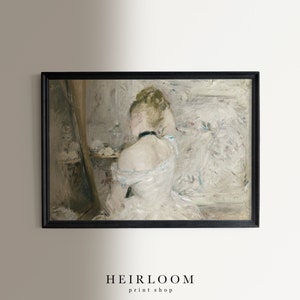 May include: A painting of a woman in a white dress, sitting in front of a mirror, with her hair up. The painting is in a black frame.