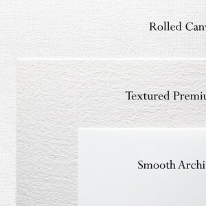 Op de afbeelding: Een close-up van drie verschillende soorten wit kunstpapier. Het bovenste gedeelte is gelabeld met "Rolled Canvas", het middelste gedeelte met "Textured Premium" en het onderste gedeelte met "Smooth Archival".