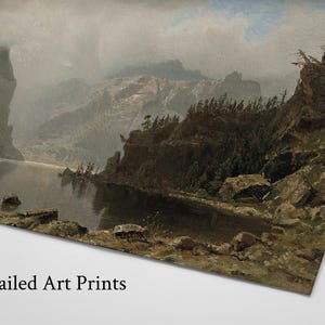 May include: A landscape art print depicts a serene lake surrounded by rocky cliffs and mountains under a cloudy sky. The artwork features muted tones of gray, brown, and green, with the text "Mailed Art Prints" at the bottom.