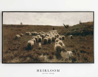 May include: A vintage painting depicting a flock of sheep being herded across a field. The sheep are white and the field is a muted brown colour. The sky is a light blue with a few clouds. The painting is framed in a black frame.