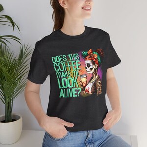 May include: Black t-shirt with a graphic of a skeleton woman with a coffee cup and the text "Does this coffee make me look alive?"