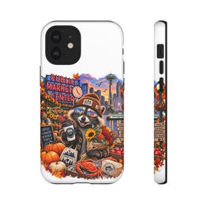 Könnte beinhalten: Eine weiße Smartphone-Hülle mit einer farbenfrohen Illustration eines Waschbären mit Mütze und Sonnenbrille, der einen Kaffeebecher und Blumen hält. Das Motiv zeigt die Skyline von Seattle, das Pike Place Market Schild, Kürbisse und einen Krebs.