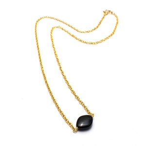 May include: A gold chain necklace with a single black gemstone pendant.