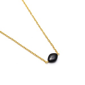 May include: A delicate gold chain necklace with a single black gemstone pendant.