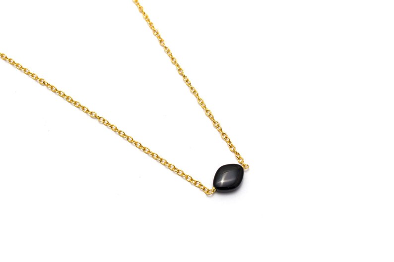May include: A delicate gold chain necklace with a single black gemstone pendant.