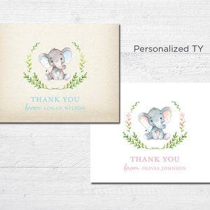 May include: Two thank you cards with a watercolor illustration of an elephant in a wreath of leaves. The card on the left has a blue wreath and the card on the right has a pink wreath. The text on the left card reads "Thank You from Logan Wilson". The text on the right card reads "Thank You from Olivia Johnson".