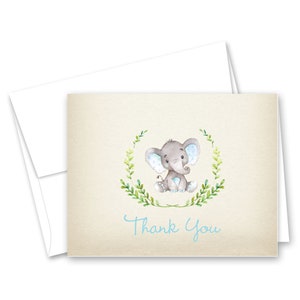 May include: A thank you card with a watercolor illustration of a gray elephant with blue ears sitting in a wreath of green leaves. The text "Thank You" is written in blue script.