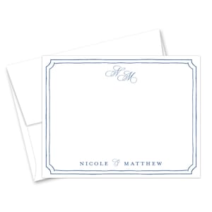 May include: A white rectangular stationery card with a blue hand-drawn style border. The card features a blue cursive monogram of the letters NM at the top center and the blue printed text NICOLE & MATTHEW at the bottom center, with an envelope.