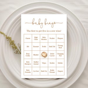 Könnte beinhalten: Eine Baby-Bingo-Spielkarte mit cremefarbenem Hintergrund und braunem Text. Die Karte zeigt ein Raster mit Babyartikeln wie 'Strampler', 'Kinderwagen' und 'Windeln'. Die Worte 'Baby Bingo' sind oben in Schreibschrift geschrieben.