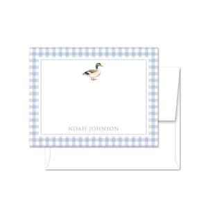 May include: A stationery set featuring a watercolor illustration of a duck. The notecard has a light blue gingham border and the name "NOAH JOHNSON" printed in a gray font. Includes a white envelope.