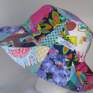 Peut inclure: Un chapeau de soleil en patchwork coloré avec une variété de motifs floraux et géométriques. Le chapeau a une large bordure et est fait de tissu en coton. Le chapeau porte une étiquette qui indique "Sew Designs 13 etsy.com/shop/SewDesigns13 Facebook: Sew Designs"