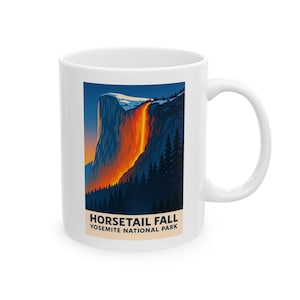 May include: White ceramic mug featuring a vibrant illustration of Horsetail Fall in Yosemite National Park. The artwork depicts a waterfall with fiery orange and red hues cascading down a cliff face, set against a dark blue sky. The mug has a curved handle.