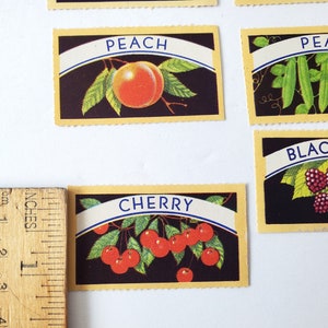 May include: Five vintage cards with illustrations of different fruits and vegetables. The cards are yellow with a black background and blue text. The cards feature a peach, peas, blackberries, cherries, and a cherry.