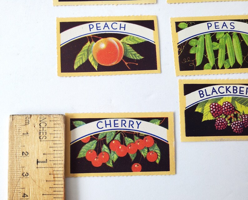 May include: Five vintage cards with illustrations of different fruits and vegetables. The cards are yellow with a black background and blue text. The cards feature a peach, peas, blackberries, cherries, and a cherry.