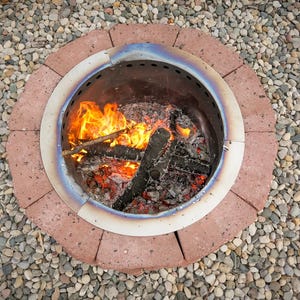 Assembled DIY smokeless fire pit with retaining wall blocks and vent blocks, glowing with a fire.
