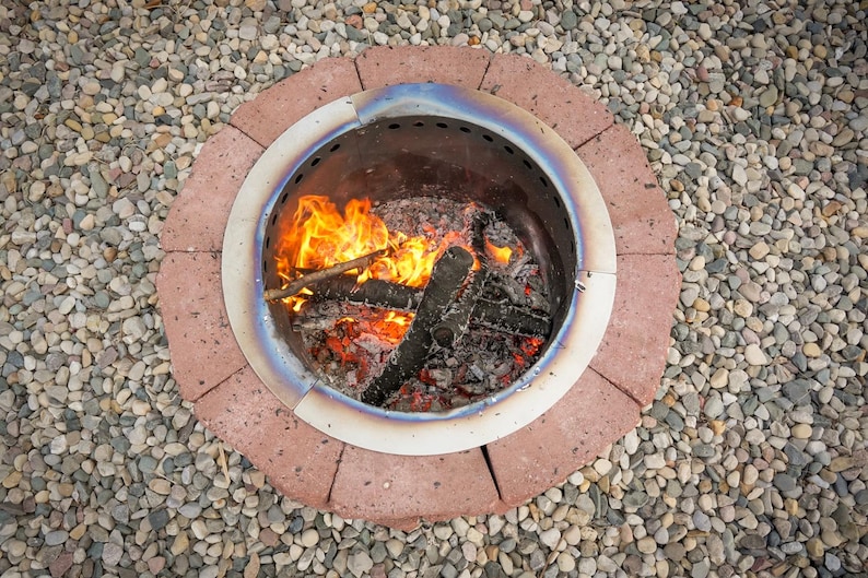 Assembled DIY smokeless fire pit with retaining wall blocks and vent blocks, glowing with a fire.