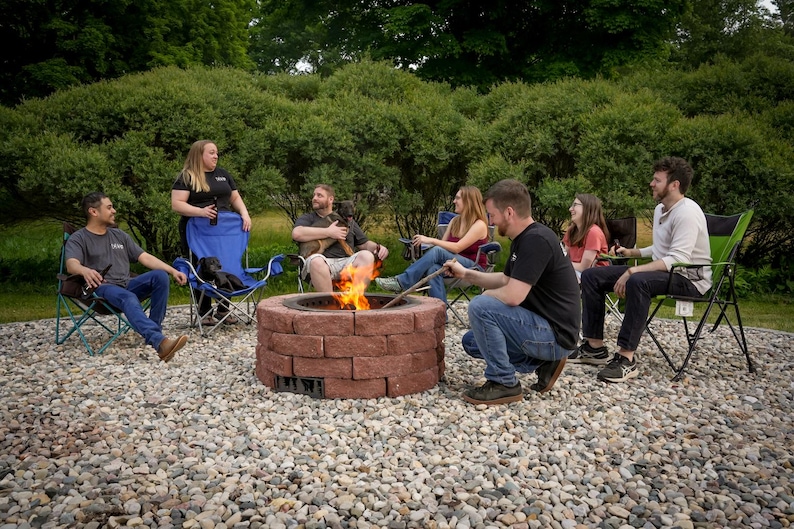 Fire pit in action with clean-burning flames and a group of friends enjoying eachother's company around it.