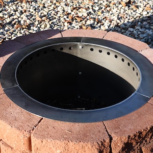 Fire ring insert with lid removed to see the vent holes at the top and bottom inside a brick fire pit ring.