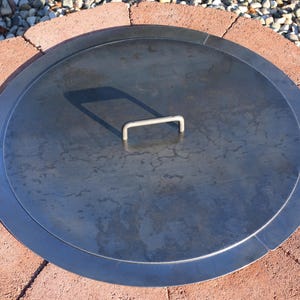 Top view of a solid steel fire pit lid, raw finish, showing durable construction and clean edges