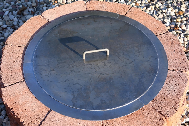 Top view of a solid steel fire pit lid, raw finish, showing durable construction and clean edges