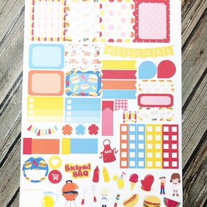 May include: A set of colorful stickers featuring a backyard BBQ theme. The stickers include a variety of designs, such as hot dogs, hamburgers, watermelon, grilling tools, and a banner that says "WEEKEND".