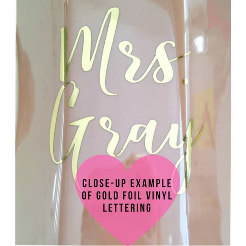 Puede incluir: Primer plano de una superficie rosa con letras de vinilo dorado que dicen "Mrs. Gray". Un coraz&oacute;n rosa con el texto "CLOSE-UP EXAMPLE OF GOLD FOIL VINYL LETTERING" est&aacute; en la esquina inferior derecha.