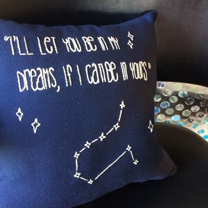 May include: A navy blue pillow with white embroidery. The pillow features the text "I'll let you be in my dreams, if I can be in yours" and a constellation of stars.