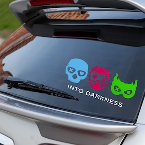 Puede incluir: Una calcomanía para ventana de coche con tres diseños de calaveras coloridas. La primera es azul claro, la segunda es roja y rosa, y la tercera es verde. El texto "INTO DARKNESS" está debajo.