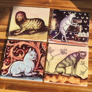 Puede incluir: Juego de cuatro posavasos cuadrados de cer&aacute;mica con ilustraciones de estilo medieval de criaturas fant&aacute;sticas y gatos. Los posavasos tienen un acabado brillante y est&aacute;n colocados sobre una superficie de madera. Cada uno tiene un dise&ntilde;o &uacute;nico.