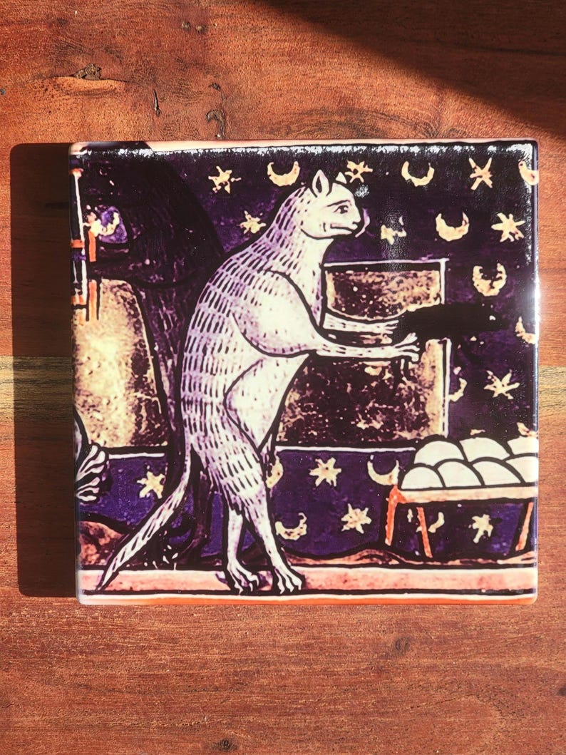 Puede incluir: Azulejo cuadrado de cer&aacute;mica con una ilustraci&oacute;n medieval de un gato. El gato, en tonos blancos y morados, est&aacute; de pie, sosteniendo un objeto oscuro. El fondo es de color p&uacute;rpura oscuro con estrellas y lunas.