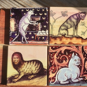 Puede incluir: Juego de cuatro posavasos cuadrados de cer&aacute;mica con ilustraciones de gatos de estilo medieval. Cada posavasos muestra un dise&ntilde;o de gato &uacute;nico en varias poses y entornos, con una est&eacute;tica vintage. Los posavasos est&aacute;n dispuestos sobre una superficie de madera.