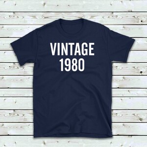 May include: A navy blue t-shirt with white text that reads "Vintage 1980".