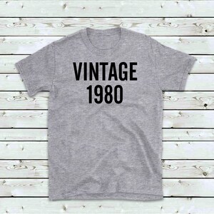 May include: A gray t-shirt with black text that reads "Vintage 1980".