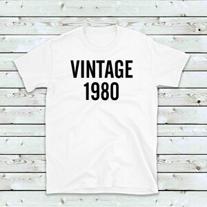 May include: White t-shirt with black text that reads "Vintage 1980".