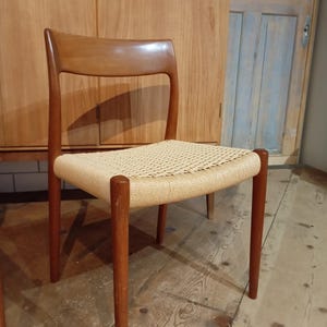 Könnte beinhalten: Ein Holzstuhl mit einem geflochtenen Sitz aus Rohrgeflecht. Der Stuhl hat ein schlichtes Design mit einer geschwungenen Rückenlehne und vier Beinen.