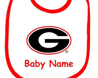 May include: White baby bib with a red trim. The bib has a black and red University of Georgia logo and the text "Baby Name".