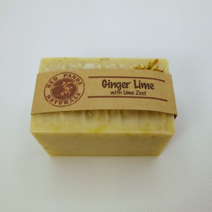 Puede incluir: Una pastilla de jabón con una etiqueta de papel marrón que dice "Red Panda Naturals" y "Ginger Lime with Lime Zest".