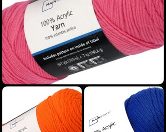 May include: Three skeins of Mainstays 100% Acrylic Yarn in vibrant colors: hot pink, bright orange, and royal blue. Each skein is labeled with details including 397 yards (363 m) and 7 oz (198.4 g).