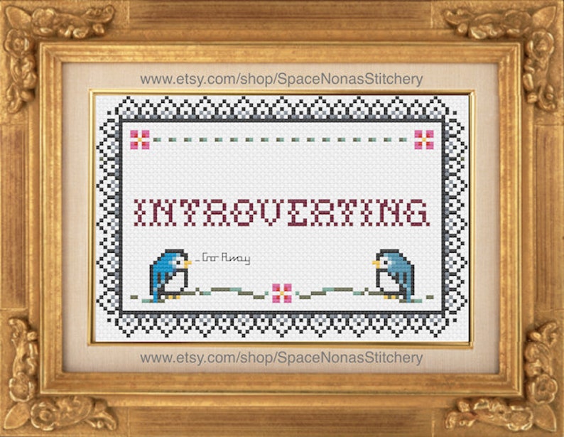May include: Cross-stitch pattern featuring a blue bird with the text "Introverting" and "Go Away" in a white frame with a black border and pink flowers.