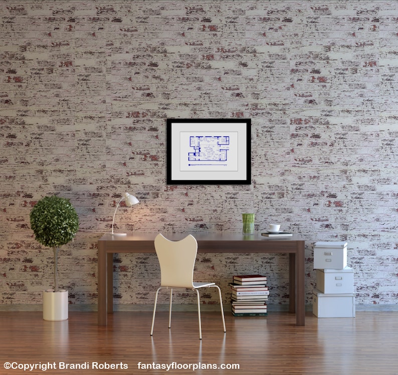 May include: A white desk chair with a curved back and a white desk with a framed blueprint hanging on a white brick wall. There are books stacked on the desk and a potted plant and a lamp on the desk.