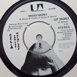Puede incluir: Un disco de vinilo blanco y negro con una imagen de Celia and the Mutations. El disco se titula "Mony Mony" y es una publicación de United Artists Records. El número de disco es UP 36262.