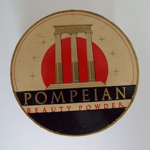 May include: Vintage round compact with a gold background and black lettering. The compact features a red sun with three gold columns in front of it. The text reads "POMPEIAN BEAUTY POWDER".